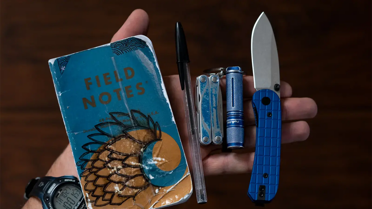 Example of a pocket dump that includes field notes, pen, knives, and flashlight