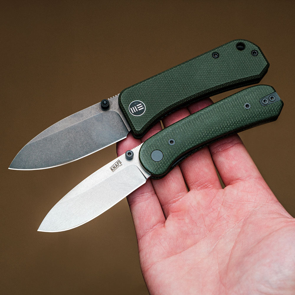 Hand holding We Banter knife and Knafs Lander knife in green micarta