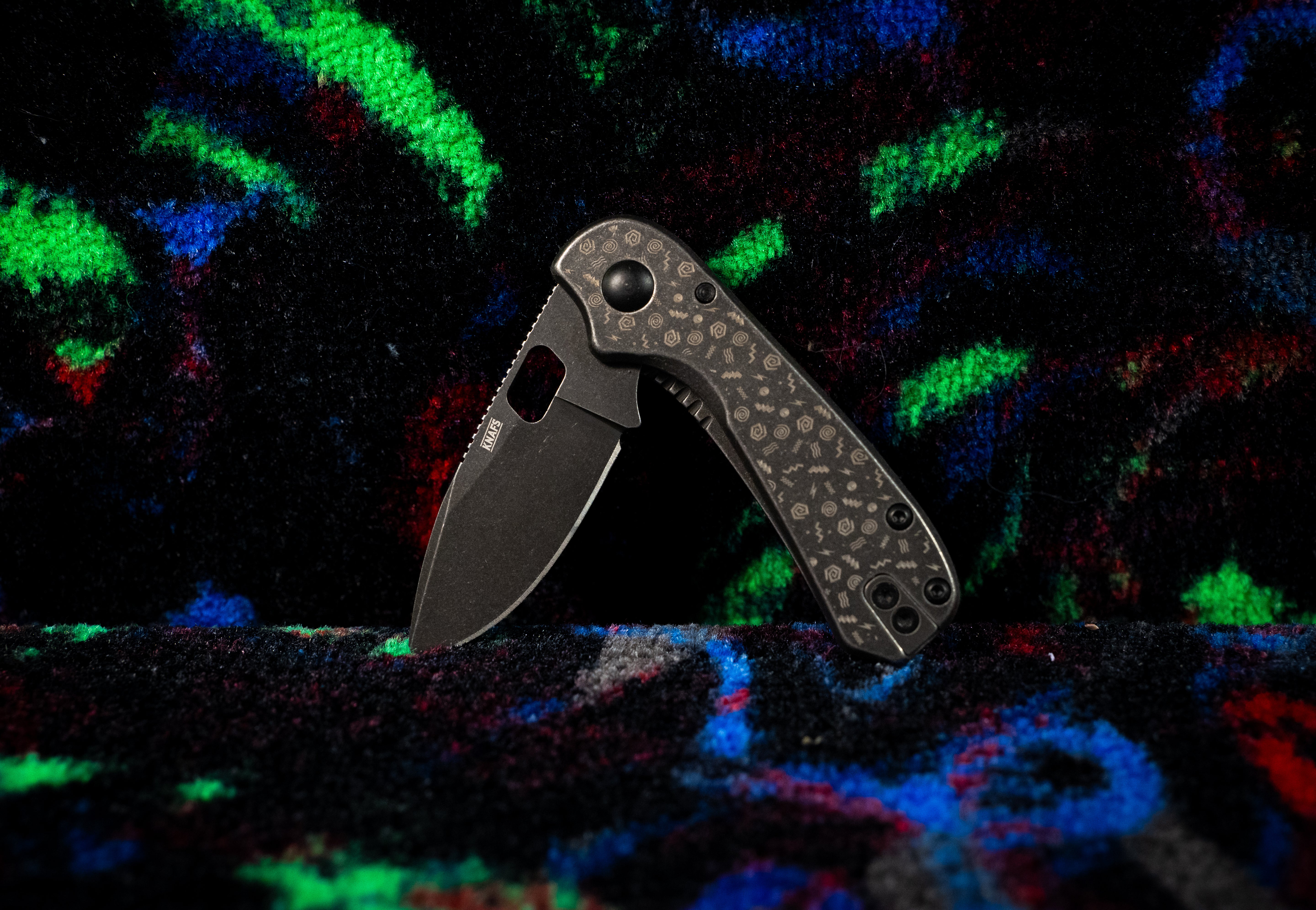 a folding pocket knife on black and neon carpet